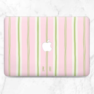 May include: A pink laptop case with a vertical striped pattern in light green and white. The Apple logo is visible in white, and the initials "R H" are printed in light green.
