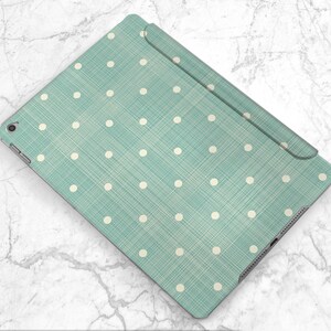 May include: A teal blue iPad case with a white polka dot pattern. The case has a textured fabric finish.