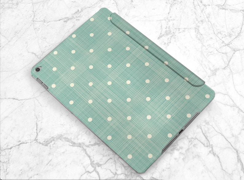 May include: A teal blue iPad case with a white polka dot pattern. The case has a textured fabric finish.