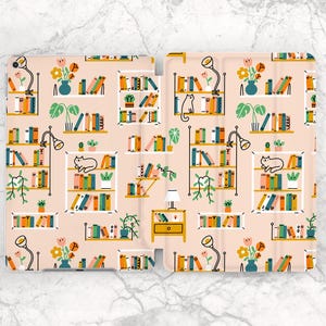 Puede incluir: Una funda de teléfono rosa y blanca con un diseño repetido de estanterías, lámparas, plantas y gatos. Las estanterías están llenas de libros coloridos.