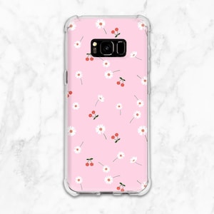 May include: A pink phone case with a clear back and a white daisy and red cherry pattern.