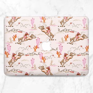 Può includere: Una custodia per laptop con un motivo ripetuto di una scena di rodeo. Il design include cowboy che cavalcano cavalli selvaggi, cactus e montagne in tonalità di rosa, arancione e marrone su uno sfondo rosa chiaro. Il logo Apple è visibile.