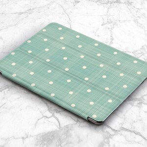 May include: A teal blue tablet case with a white polka dot pattern. The case has a textured fabric finish.