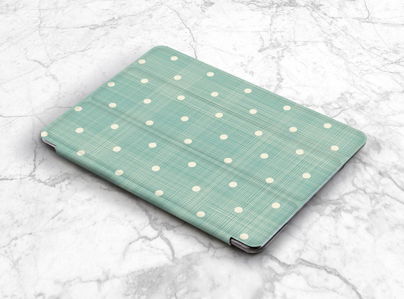 May include: A teal blue tablet case with a white polka dot pattern. The case has a textured fabric finish.