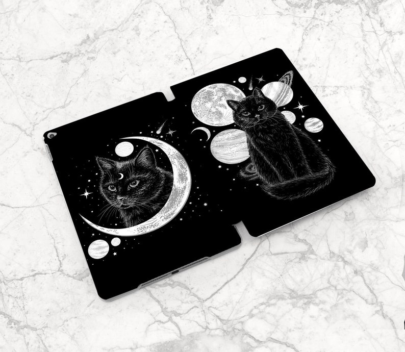 May include: Black and white illustration of two black cats with crescent moons and stars on a black background. The cats are surrounded by planets and stars.