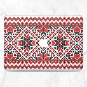 May include: A laptop case featuring a geometric pattern in red, black, and white. The design includes repeating floral and diamond shapes, with a white Apple logo visible. The case has a glossy finish.