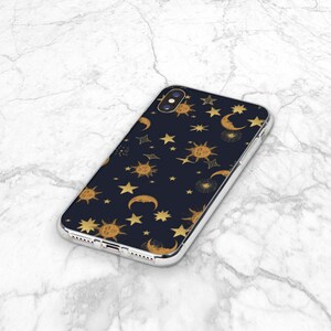 May include: A clear phone case with a black background and a gold pattern of suns, moons, and stars.