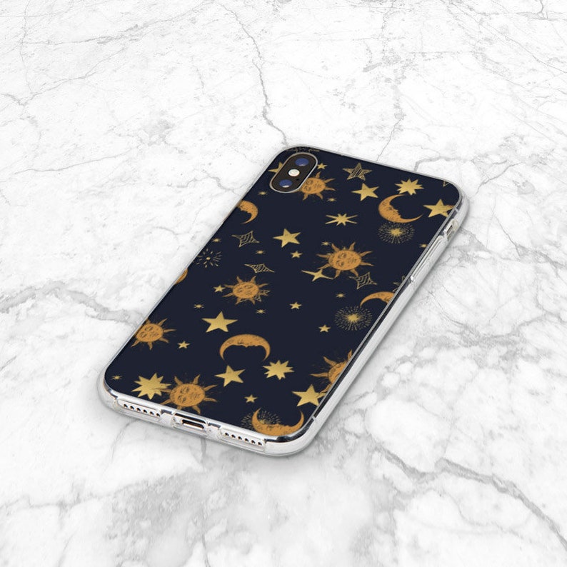 May include: A clear phone case with a black background and a gold pattern of suns, moons, and stars.