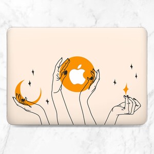 May include: A laptop case with a cream background featuring a minimalist design. The design includes outlined hands holding an orange circle with a white apple logo, a crescent moon, and stars.