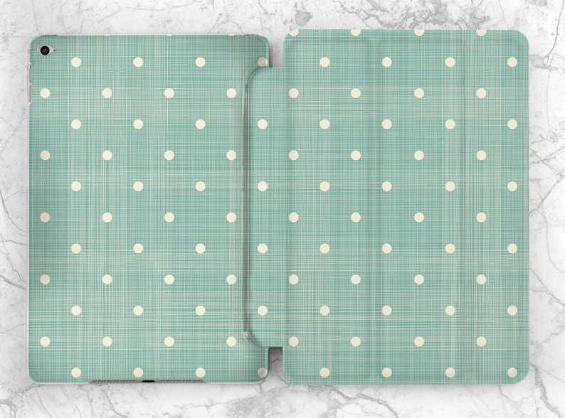 May include: A teal blue iPad case with a white polka dot pattern and a subtle woven texture.