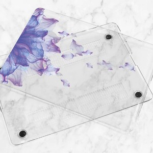 May include: A clear plastic laptop case with a floral design. The design features purple and blue watercolor flowers on a white background.