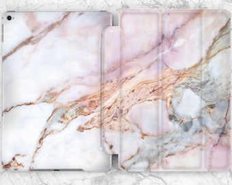 May include: A pink and white marble iPad case with a folio style cover. The case has a subtle pink and gold veining pattern.