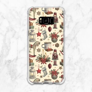 Puede incluir: Una funda transparente para teléfono con fondo blanco y un patrón repetitivo de ilustraciones con temática navideña. Las ilustraciones incluyen un caballo de balancín, un cascanueces, una media, una linterna, una taza, una vela y un bastón de caramelo.