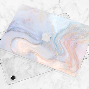 Puede incluir: Una funda para port&aacute;til de pl&aacute;stico transparente con un dise&ntilde;o de patr&oacute;n de m&aacute;rmol. La funda tiene un patr&oacute;n de m&aacute;rmol de color azul claro, rosa y blanco con detalles dorados. La funda est&aacute; dise&ntilde;ada para adaptarse a un port&aacute;til.