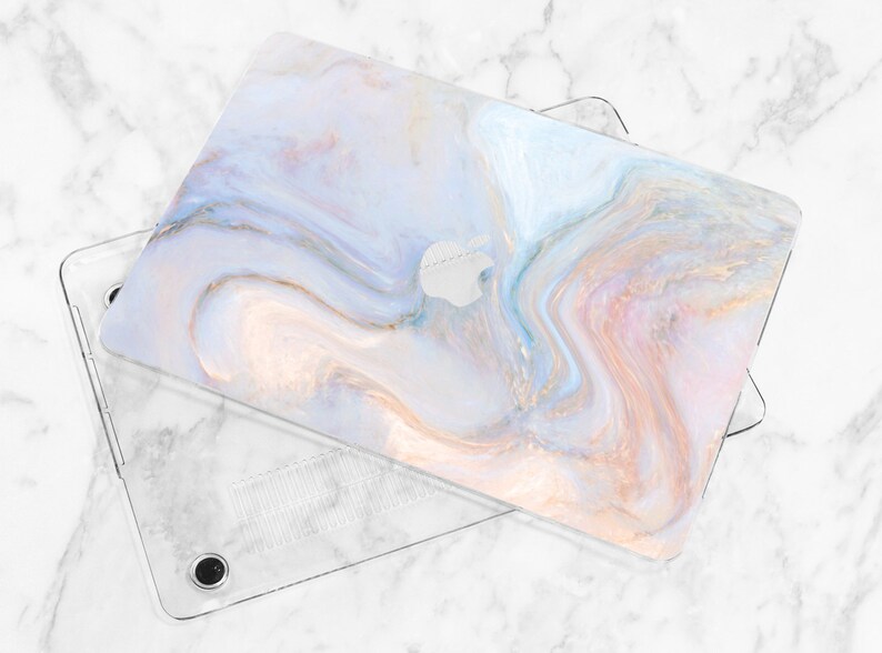 Puede incluir: Una funda para port&aacute;til de pl&aacute;stico transparente con un dise&ntilde;o de patr&oacute;n de m&aacute;rmol. La funda tiene un patr&oacute;n de m&aacute;rmol de color azul claro, rosa y blanco con detalles dorados. La funda est&aacute; dise&ntilde;ada para adaptarse a un port&aacute;til.