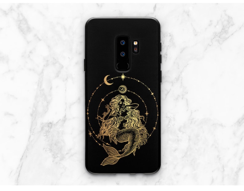May include: Black phone case with a gold mermaid design. The mermaid is surrounded by a circle of stars and moons.