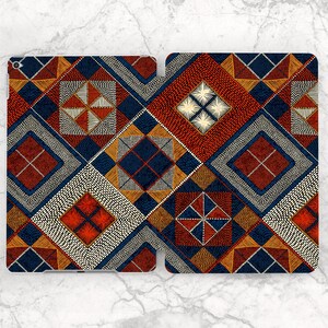 Peut inclure: Une housse de tablette à motifs avec un design géométrique dans les tons de rouge, bleu marine, orange et blanc. L'étui est ouvert, révélant l'intérieur. Le motif comprend des carrés, des losanges et des triangles.