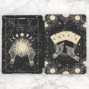May include: Black tablet case with a celestial design. The case features a sun, crescent moons, stars, and hands holding tarot cards. The design is in cream and gold against a black background. The case is open, revealing the interior.