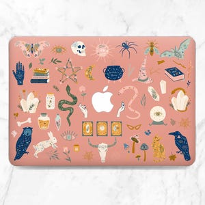 May include: A pink laptop case featuring a whimsical design with various mystical elements. The case includes illustrations of a skull, snake, owl, and tarot cards. Other designs include a cauldron, crystals, and a witch's hat.