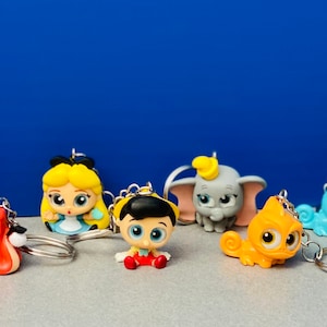 May include: A collection of 10 colorful Disney character keychains. The keychains feature characters like Peter Pan, Alice in Wonderland, Dumbo, and Stitch. Each keychain is made of plastic and has a metal ring for attaching to keys.