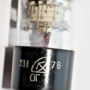May include: A black and silver vacuum tube with the text "XII OF 76" printed on the side.