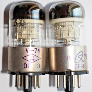 May include: Two vintage vacuum tubes with silver metal casings and glass tops. The tubes are labeled "V-71" and "V-78" with the text "OG 3" on both.