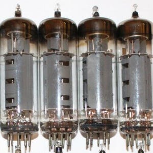 May include: Five vintage vacuum tubes with glass enclosures and metal bases. The tubes have a silver-colored metal grid inside the glass. The tubes are arranged in a row.