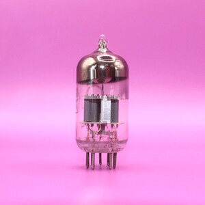 May include: A clear glass valve with a silver-coloured top and multiple pins at the base. Inside, there are dark grey components and delicate wiring. The background is a solid pink.