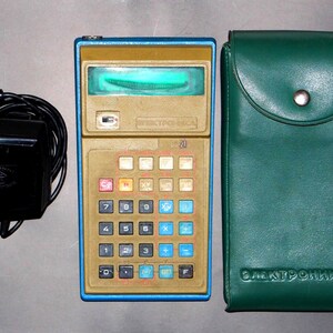 Può includere: Calcolatrice Elektronika MK-21 vintage con custodia oro e blu, numerosi pulsanti e display verde. Include un adattatore di alimentazione nero e una custodia in pelle verde con testo in rilievo.