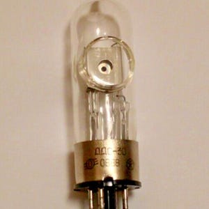 May include: A clear glass vacuum tube with a metal base and a circular metal ring around the top. The base has the text "00C-30" and "0838" printed on it.
