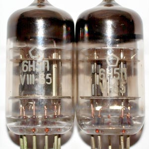 May include: Two vintage 6H5N VIII-35 vacuum tubes with silver caps and clear glass bodies. The tubes have a hexagonal logo and are in good condition.