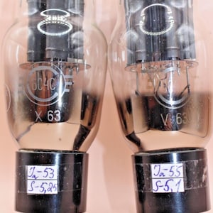 Puede incluir: Dos tubos de vacío 6C4C vintage con bases negras y envoltorios de vidrio. Los tubos están etiquetados con "X 63" y "V 63" y tienen fechas y números escritos a mano en las bases.