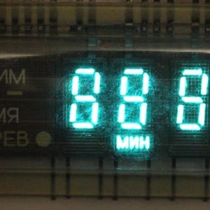 Może przedstawiać: Cyfrowy timer z zielonym wyświetlaczem pokazującym 88:88. Timer ma etykiety w języku rosyjskim dla "trybu", "czasu" i "ciepła".