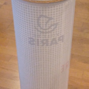 Peut inclure: Un panier à linge cylindrique blanc avec un couvercle moucheté comportant deux découpes rectangulaires. Le corps du panier est en maille blanche, et le mot "PARIS" est visible sur le côté.