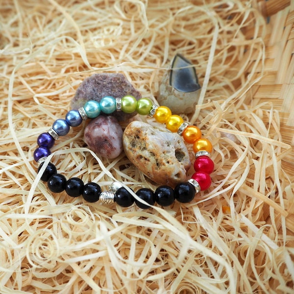 bracelet élastique 7chakras en perles de verre noires, couleurs nacrées 8mm, rondelles strass perle 6mm sur bélière. Envoi en lettre suivie.