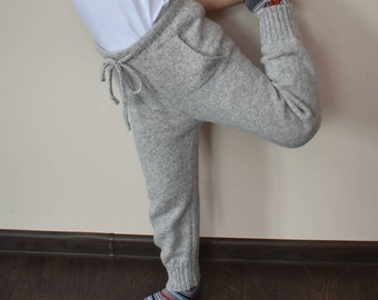 Puede incluir: Una camiseta blanca lisa de manga corta combinada con pantalones de chándal de punto gris claro con cintura de cordón y puños acanalados. Los pantalones tienen dos bolsillos delanteros y se usan con calcetines a rayas en azul, gris y naranja.