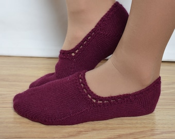 Può includere: Un paio di calzini da pantofola in maglia color borgogna con un delicato motivo a pizzo intorno alla caviglia.