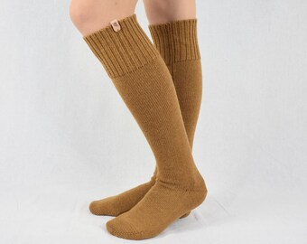 May include: A pair of knee-high socks in a warm, golden-brown color. The socks are made of a ribbed knit material and have a folded cuff at the top. A small, rectangular tag is attached to the cuff of one sock.