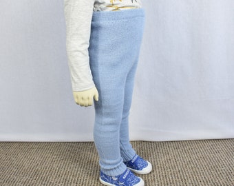 Puede incluir: Leggings de punto azul claro con cintura alta y puños acanalados en los tobillos. Los leggings se llevan con una camiseta de manga larga con un estampado gráfico en dorado y negro y zapatillas azules estampadas con suela blanca y el texto ADVENTURE.