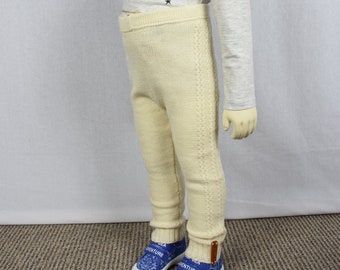 May include: Cream-colored knit leggings featuring a ribbed waistband and a vertical cable knit pattern running down the outer side of each leg. The leggings have ribbed cuffs at the ankles and a small brown rectangular tag attached to the lower hem.