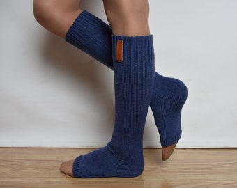 May include: A pair of knee-high, ribbed knit socks in a deep blue color. These open-toe socks feature a small, rectangular brown leather-like tag attached to the upper cuff of the left sock, providing a subtle contrast to the blue fabric.