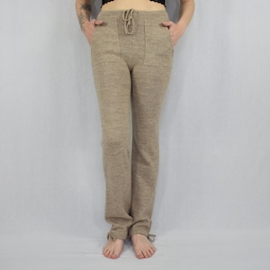 Puede incluir: Pantalones de punto beige con cintura de cord&oacute;n, dos bolsillos delanteros y peque&ntilde;as cintas en la parte inferior de cada pierna. Los pantalones tienen una silueta de pierna recta y una apariencia texturizada y jaspeada en toda la tela.