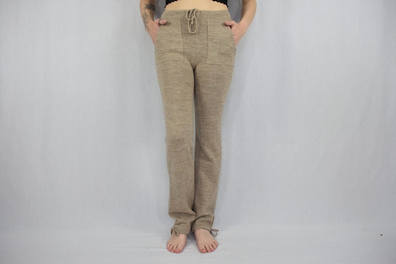 Puede incluir: Pantalones de punto beige con cintura de cord&oacute;n, dos bolsillos delanteros y peque&ntilde;as cintas en la parte inferior de cada pierna. Los pantalones tienen una silueta de pierna recta y una apariencia texturizada y jaspeada en toda la tela.