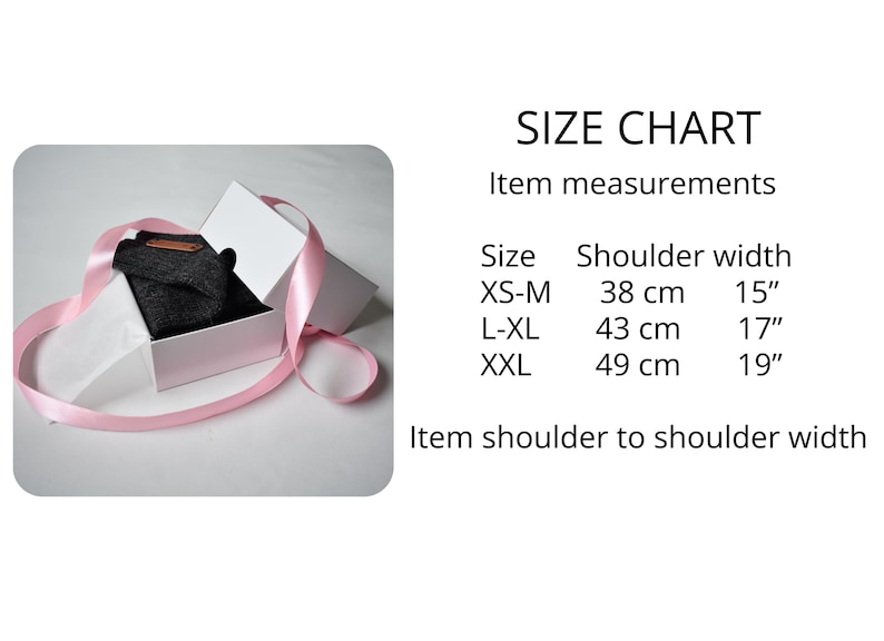 May include: A dark grey garment inside a white gift box wrapped with a pink ribbon. A size chart is displayed with the text: SIZE CHART, Item measurements, Size, Shoulder width, XS-M 38 cm 15", L-XL 43 cm 17", XXL 49 cm 19", Item shoulder to shoulder width.