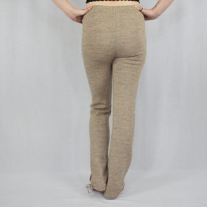 Puede incluir: Un pantal&oacute;n de tiro alto y largo completo en tejido de punto jaspeado de color marr&oacute;n claro s&oacute;lido. El pantal&oacute;n presenta una silueta ajustada en caderas y muslos con corte de pierna recta, cintura limpia y una costura central vertical visible.