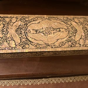 May include: A rectangular box featuring intricate mother-of-pearl inlay on a dark surface. The lid displays two central cranes surrounded by floral motifs and butterfly patterns, with a geometric border pattern framing the entire top edge.