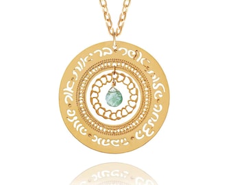 May include: Gold-toned pendant necklace with a circular design featuring Hebrew text. The pendant has a layered appearance with intricate cut-out patterns and a central, teardrop-shaped, light green gemstone. The necklace chain is also gold-toned.