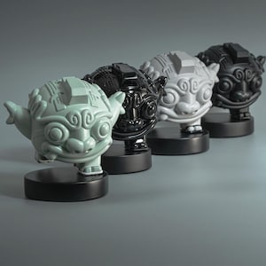 May include: Four ceramic sculptures of stylized mythical creatures in a row. The sculptures are in shades of green, black, gray, and black. Each sculpture is mounted on a black circular base. The background is a solid gray.