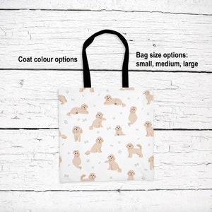 May include: A white tote bag with a black handle and a pattern of beige doodle dogs. The text "Coat colour options" is at the top left and "Bag size options: small, medium, large" is at the top right.
