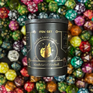 Puede incluir: Vela negra con letras doradas que dicen "Item Get Hidden Loot Candles" y "Ninth Level Fireball". La vela est&aacute; rodeada de dados de colores.